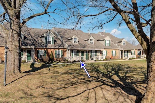 cape cod home with a front lawn and brick siding