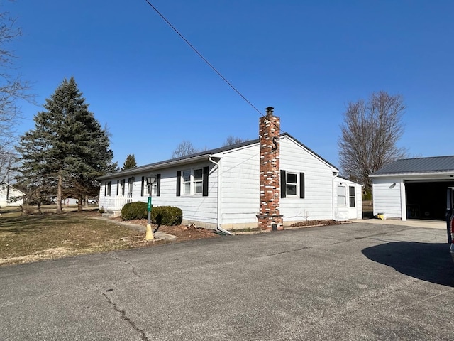 380 W Neff St, Morral, OH 43337 - view of side of home with a garage, driveway, an outdoor structure, and a chimney