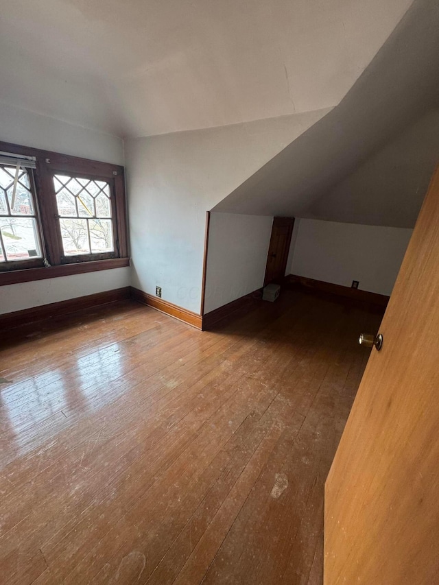 additional living space featuring baseboards, lofted ceiling, and hardwood / wood-style flooring