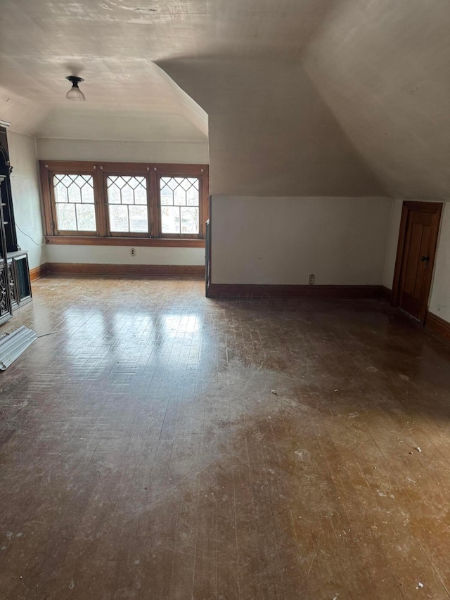 additional living space with baseboards, lofted ceiling, and hardwood / wood-style flooring