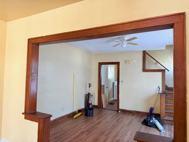 exercise area with ceiling fan, a textured ceiling, baseboards, and wood finished floors