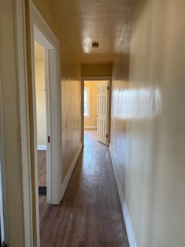 corridor featuring baseboards and dark wood-style flooring