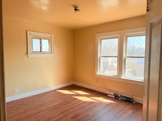 spare room featuring wood finished floors, baseboards, and a wealth of natural light