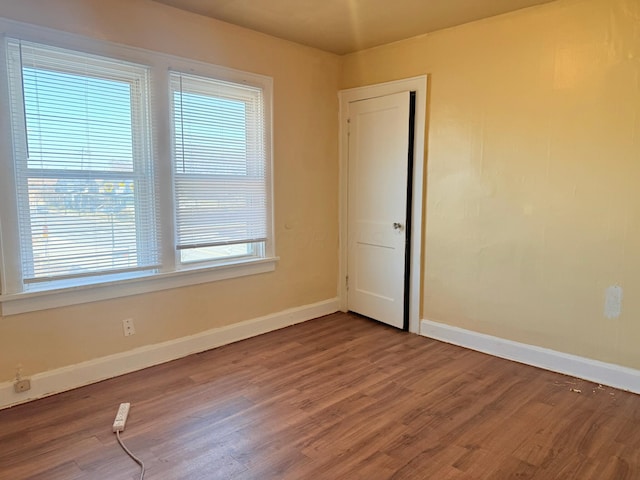 spare room featuring baseboards and wood finished floors