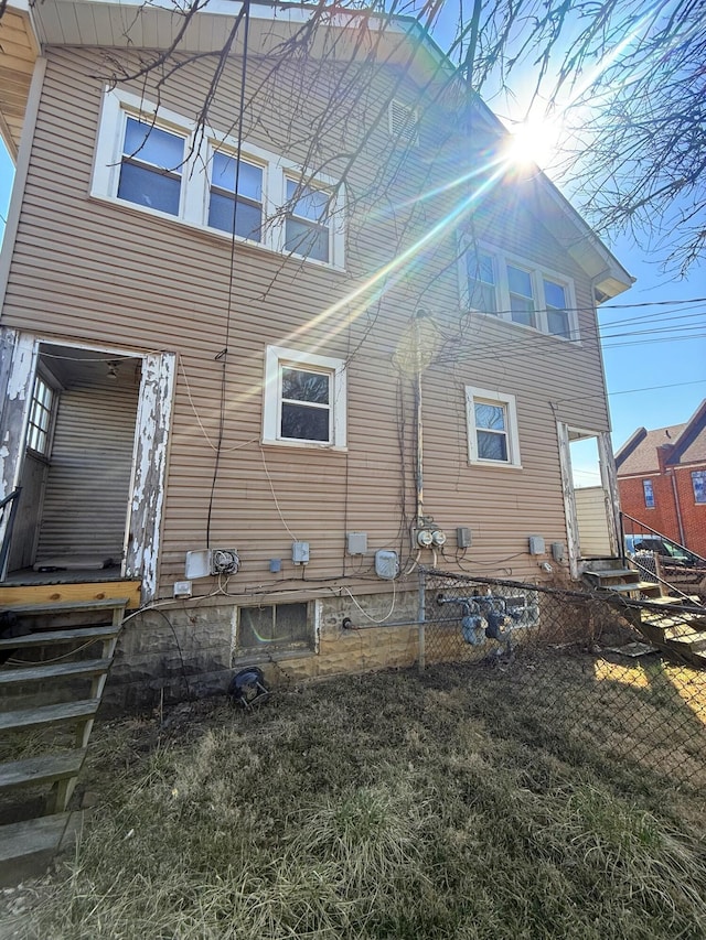 rear view of property with entry steps and fence