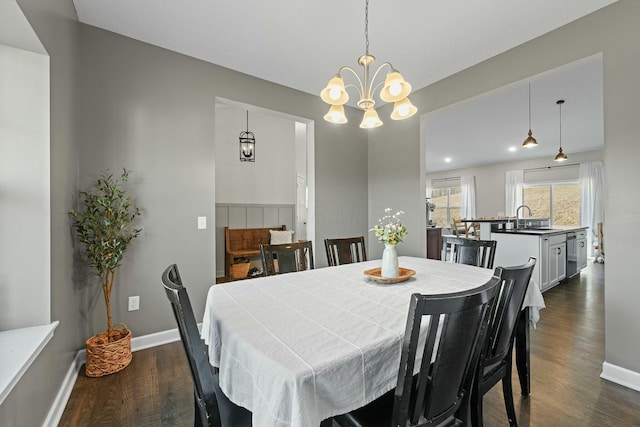 dining space with dark wood-style floors, a chandelier, and baseboards