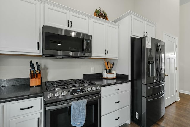 kitchen with dark wood-style floors, dark countertops, appliances with stainless steel finishes, and white cabinets