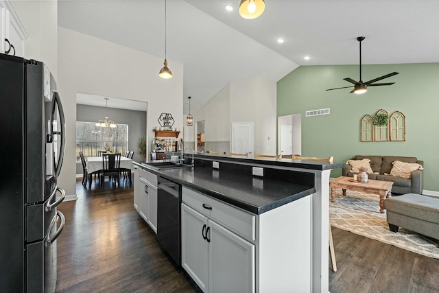 kitchen featuring visible vents, a sink, dark countertops, open floor plan, and black fridge