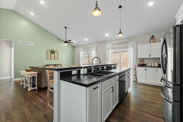 kitchen with dark countertops, visible vents, open floor plan, stainless steel appliances, and a sink