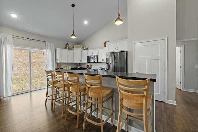 kitchen with dark countertops, white cabinets, stainless steel appliances, and dark wood-type flooring