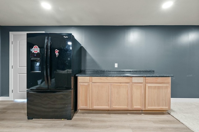 bar featuring baseboards, black fridge with ice dispenser, and light wood finished floors