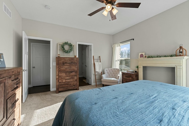 bedroom featuring visible vents, light colored carpet, baseboards, and ceiling fan