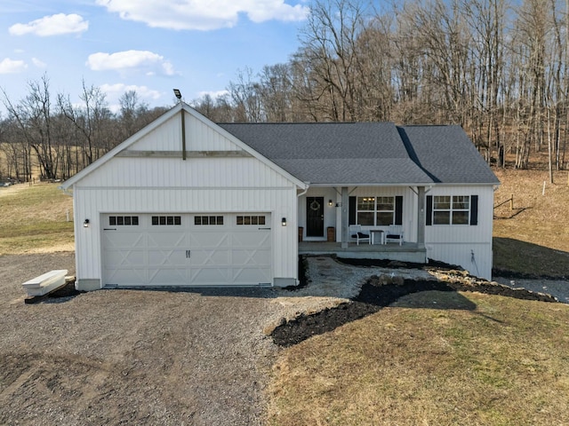 view of front of home with a garage, covered porch, driveway, and a shingled roof