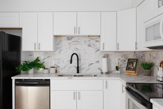 kitchen with white microwave, freestanding refrigerator, a sink, white cabinets, and dishwasher