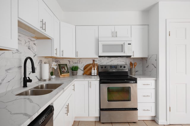 kitchen with white cabinets, light stone counters, appliances with stainless steel finishes, and a sink