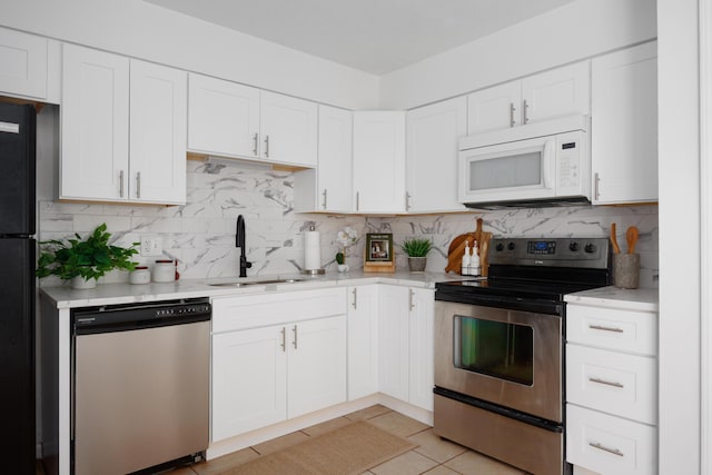 kitchen with backsplash, light tile patterned flooring, white cabinets, stainless steel appliances, and a sink