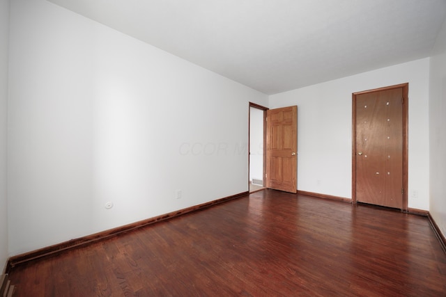 empty room with baseboards and dark wood-style flooring