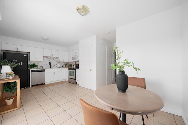 kitchen featuring a sink, backsplash, stainless steel appliances, white cabinets, and light countertops