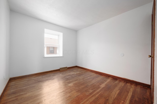 empty room featuring visible vents, baseboards, and wood finished floors