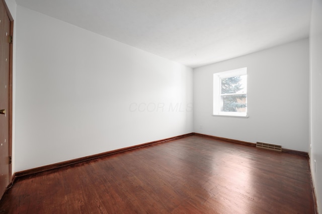 unfurnished room featuring visible vents, baseboards, and wood finished floors