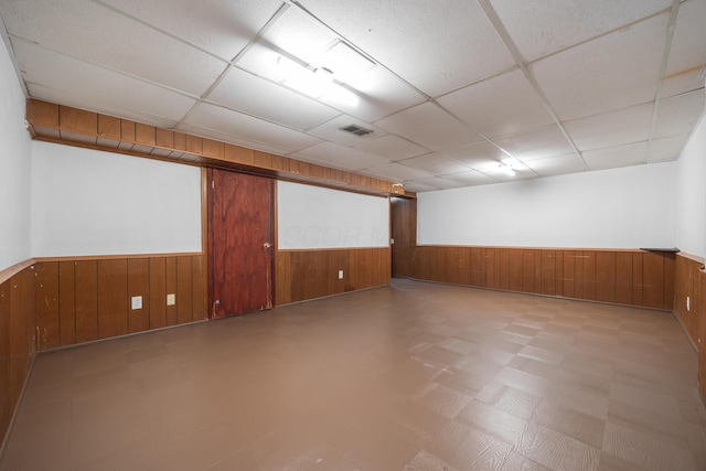 finished basement featuring tile patterned floors, visible vents, wainscoting, and wooden walls