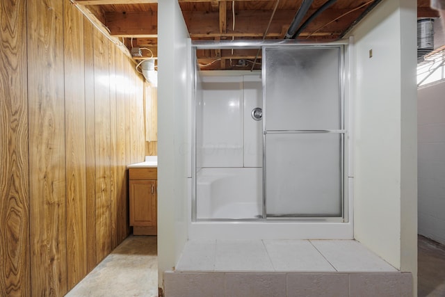 bathroom featuring concrete floors, wood walls, and a shower stall