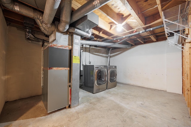 unfinished below grade area featuring heating unit and washer and clothes dryer