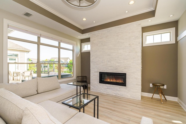 living room featuring baseboards, visible vents, a fireplace, ornamental molding, and light wood-style floors