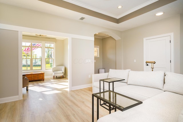 living room with baseboards, light wood-style flooring, recessed lighting, arched walkways, and crown molding