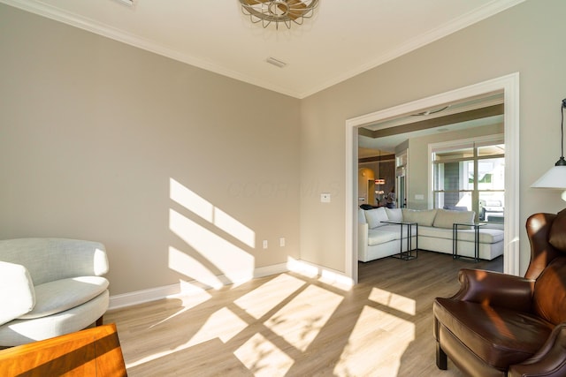 living area featuring visible vents, wood finished floors, baseboards, and ornamental molding