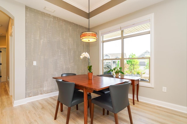 dining room with visible vents, crown molding, baseboards, light wood-style flooring, and arched walkways