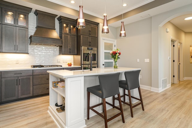 kitchen featuring visible vents, premium range hood, arched walkways, stainless steel appliances, and open shelves