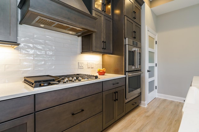 kitchen featuring light countertops, custom range hood, backsplash, and stainless steel appliances