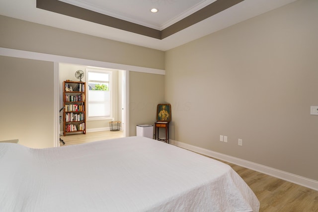 bedroom featuring crown molding, baseboards, recessed lighting, light wood-style flooring, and a raised ceiling