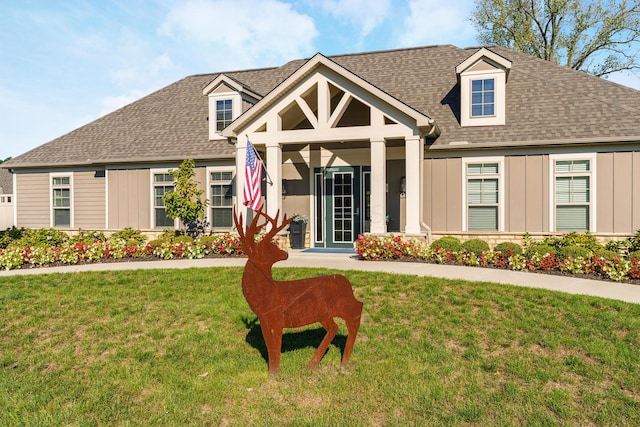 view of front of property with board and batten siding, a front lawn, and a shingled roof