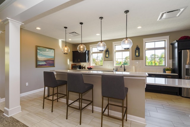 kitchen with visible vents, light countertops, a kitchen breakfast bar, tasteful backsplash, and a center island