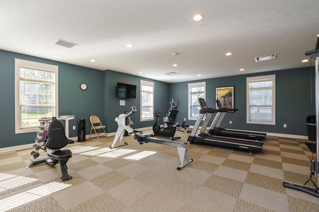 exercise room with visible vents, recessed lighting, a healthy amount of sunlight, and baseboards