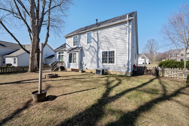 back of property with a fenced backyard, a lawn, and central AC