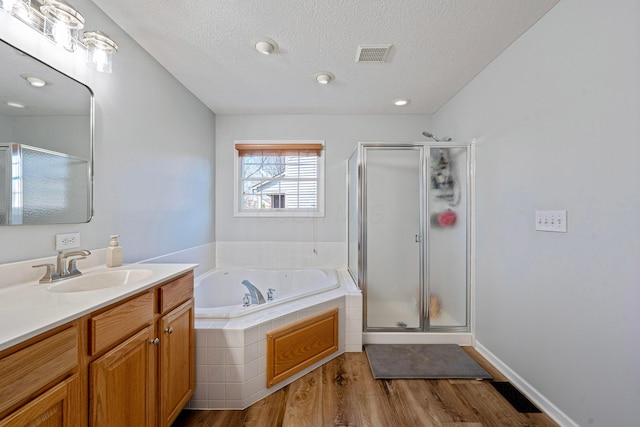 bathroom featuring a stall shower, visible vents, a bath, and vanity