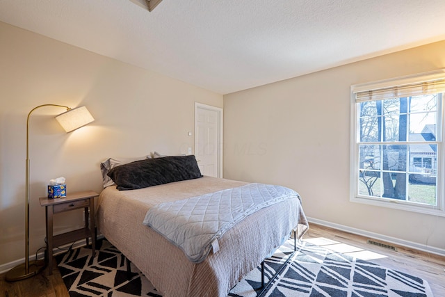 bedroom featuring visible vents, baseboards, and wood finished floors