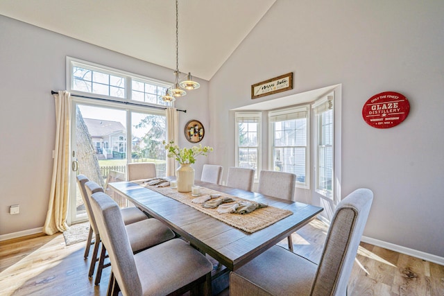 dining room featuring an inviting chandelier, baseboards, light wood finished floors, and high vaulted ceiling