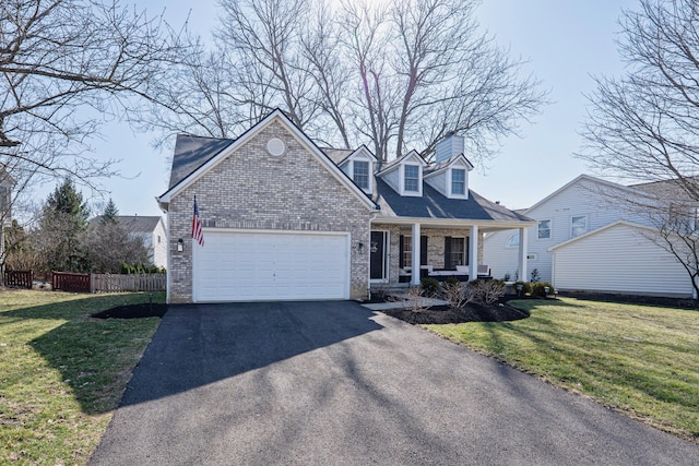 new england style home featuring fence, a front yard, covered porch, a garage, and driveway