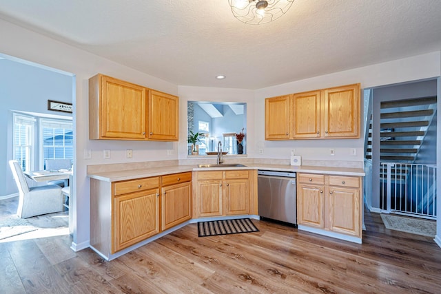 kitchen featuring dishwasher, light countertops, light wood-style flooring, a textured ceiling, and a sink