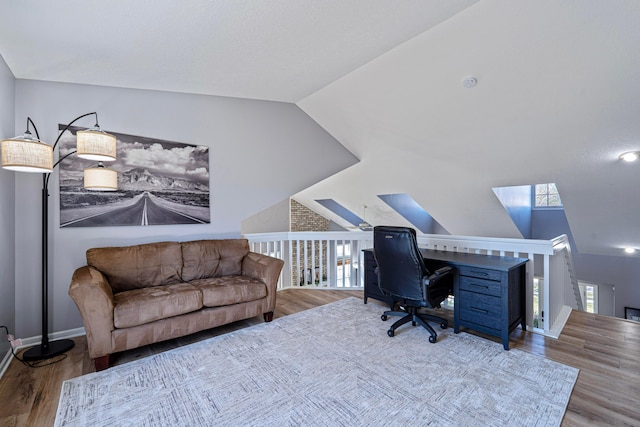 office with vaulted ceiling with skylight, baseboards, and wood finished floors