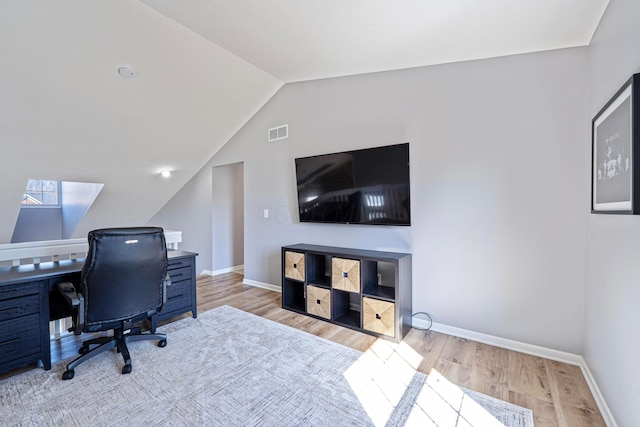 home office featuring vaulted ceiling with skylight, wood finished floors, visible vents, and baseboards