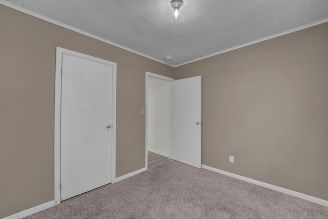 unfurnished bedroom featuring crown molding, carpet flooring, and baseboards