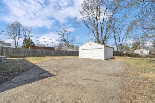 view of yard featuring a garage, central AC, an outdoor structure, and fence