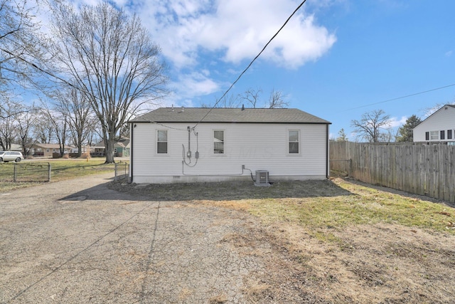 back of property featuring crawl space, central AC, dirt driveway, and fence