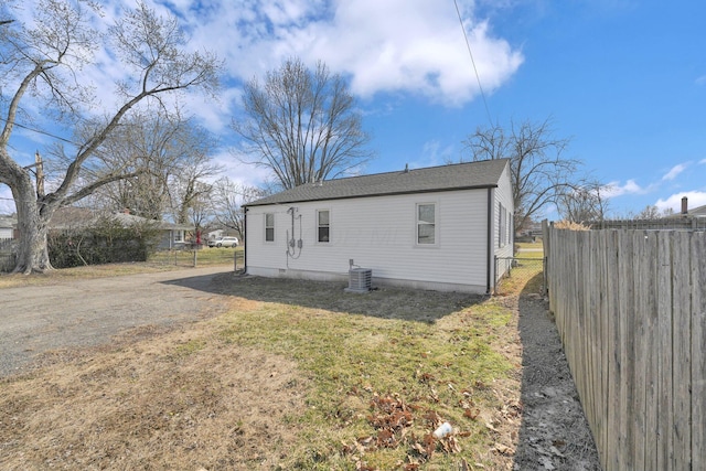 back of house with cooling unit, driveway, a lawn, and fence