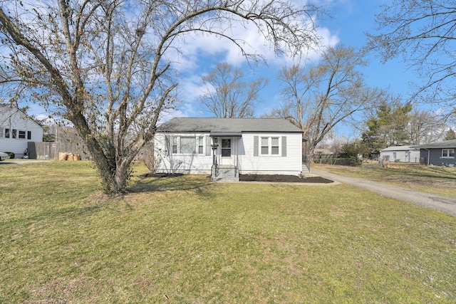 view of front of house featuring aphalt driveway, a front lawn, and fence